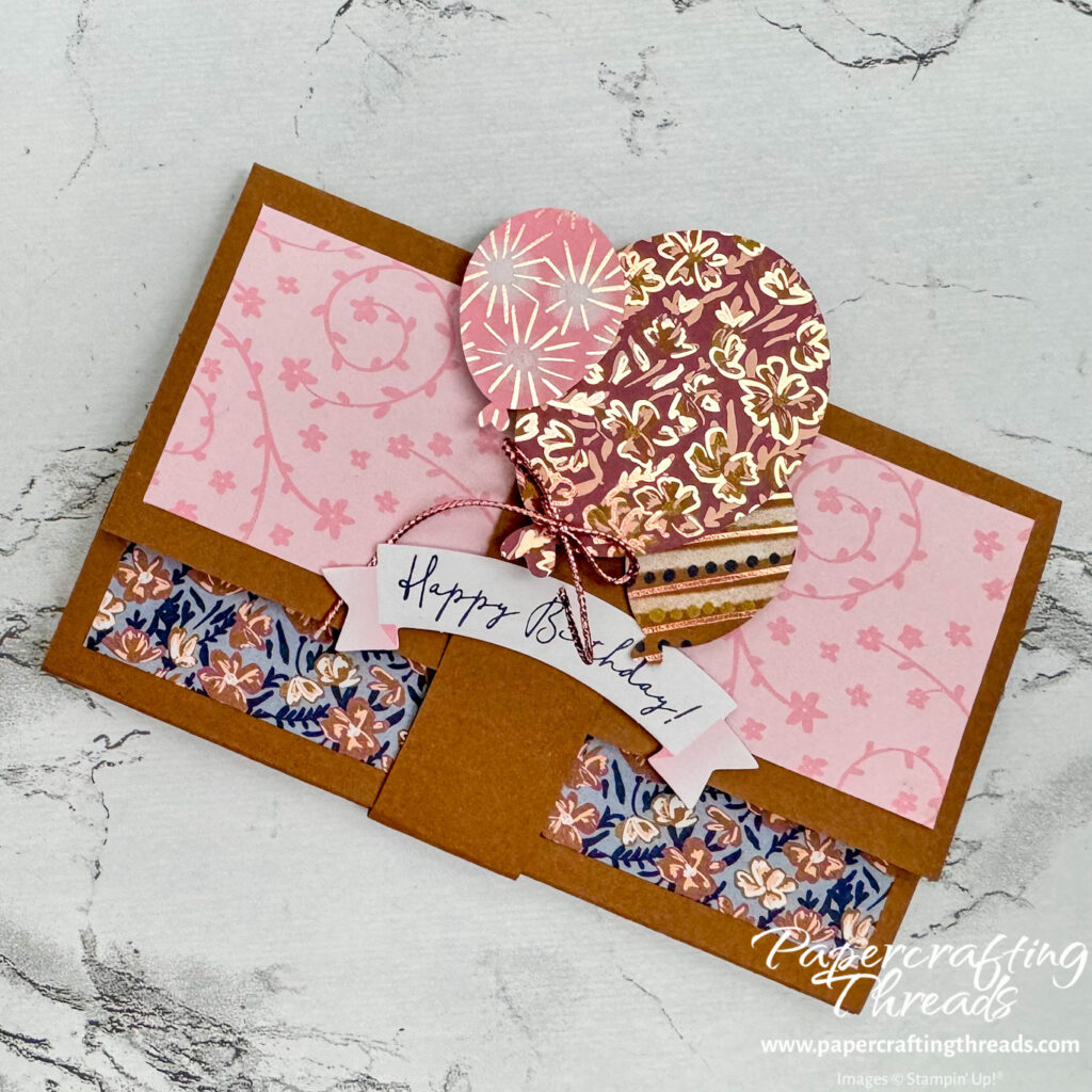 Pop Up Gift Card Holder shows a wallet style holder in Pecan Pie cardstock with pink and blue floral patterns decorating the flaps. A matching belly band wraps around the holder and is decorated with balloons and a happy birthday banner