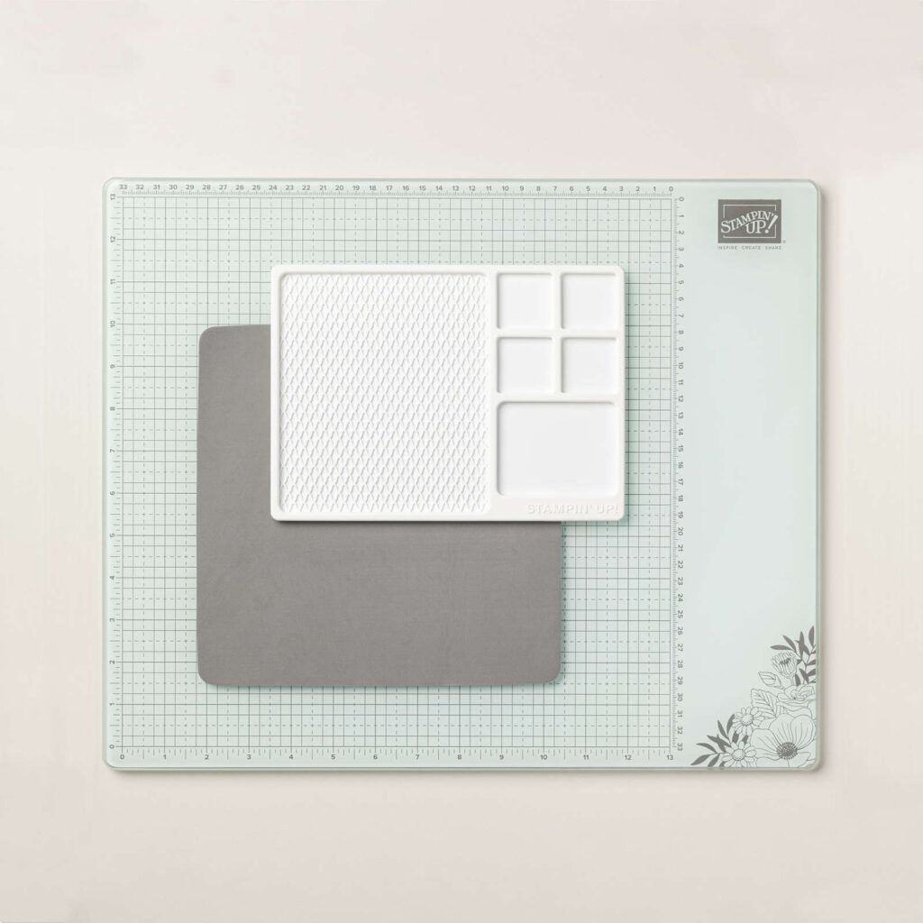Stampin’ Glass Mat Studio consists of a heavy-duty glass mat printed with a ruler and grid lines, a cleaning cloth and a nonslip, heat resistant, waterproof silicone mat featuring four palette squares for mixing custom ink colors or for holding small ink spots in place while crafting. Each component can be used separately or you can use all three items together.