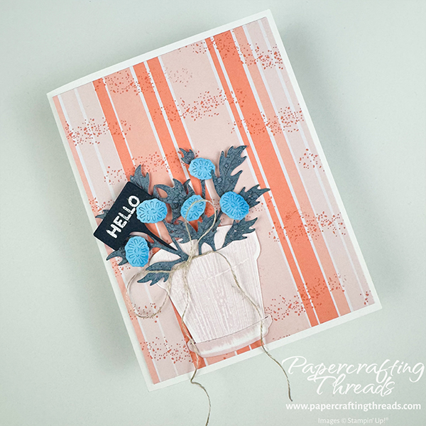 Complementary Crisp Cantaloupe color scheme card. Card features Crisp Cantaloupe vertical stripes with stamped splotches. Flower pot with bright blue florals, darker leaves and a cheery 'Hello' plant pick