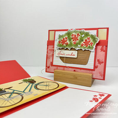 Easy Little Fun Fold card alternative for Bikes & Blooms Paper Pumpkin kit. Cards are shown both open and closed. Open version Front has white flap extending down from the top of the landscape card. A tan woven basket full of flowers fills the flap. Sentiment is best wishes with a linen thread bow. A coral colored lower flap that flips up under the upper flap is covered in tone on tone little butterflies. Closed version: Coral colored card base extends above center focal point of a bicycle with plants and books in the baskets. White liner lower panel has stamped flowers in the lower right corner.