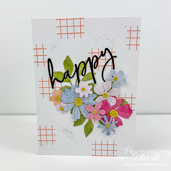 Hidden Shadowbox Fun Fold card alternative for July 2026 Hooray for Birthdays Paper Pumpkin Kit. Front view of a white card base with watercolored floral die cuts in peach, soft pink, soft blues and soft purples. Front has large black greeting of 'happy' along with large spray of florals and greenery with a cross hatch of orange in the background and black splatters of ink.