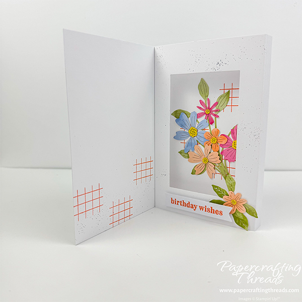 Hidden Shadowbox Fun Fold card alternative for July 2026 Hooray for Birthdays Paper Pumpkin Kit. Inside view of a white card base with watercolored floral die cuts in peach, soft pink, soft blues and soft purples. Inner left of card has shadowbox with large floral spray showcased inside the 'box', sentiment of 'birthday wishes' along the bottom and another peachy blossom and greenery. Inner right has more of the orange crosshatch pattern and black splatters.
