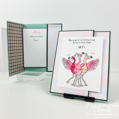 Secret Slider Cards shown closed and open. Card on right that is closed has a Pool Party base, with Early Espresso layers behind Barely Blush stripes and dots patterns. Three pink flamingos grace the front with the greeting "this is your birthday song...it isn't very long! HEY!" The open card shows the sentiment 'happy birthday to you' sliding out from a polka dotted pocket on the inside right of the card and a bronze metallic check pattern on the inside left.