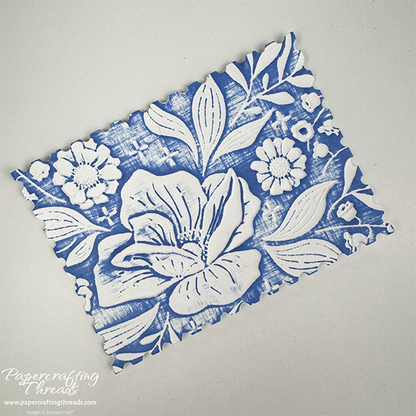 Debossed card panel with floral spray and blue ink swiped across once vertically