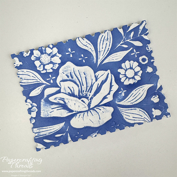 Embossing folder technique with the debossed side of a floral spray swiped multiple times with blue ink.