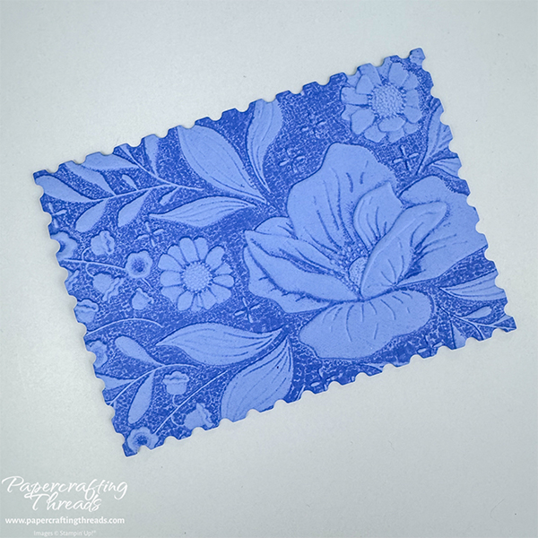 Embossing folder technique of adding ink to the inside of the embossing folder before running through a cut & emboss machine. Floral image is in relief with dark blue background.