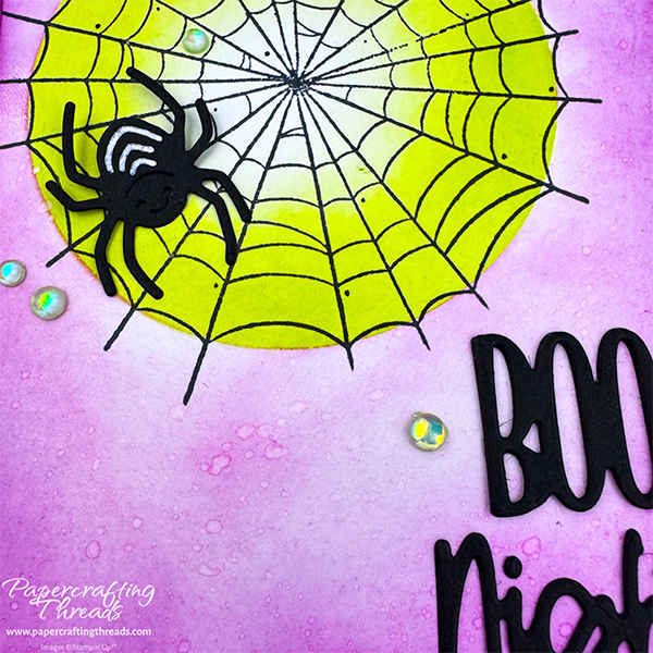 Spooky Halloween themed greeting card with multiple Inking techniques. Berry Burst ink goes from darker to lighter center of black spider web. Lime green background behind web. Large black spider with white stripes sits on web. Greeting in lower right corner is 'BOO Night' in die cut black letters. Opal gems scattered across front.