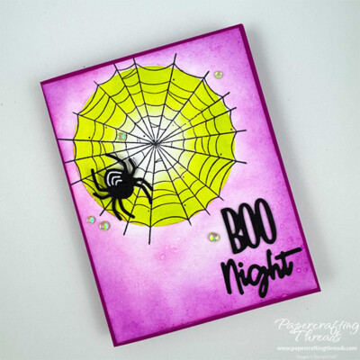 Spooky Halloween themed greeting card showing Inking Techniques. Berry Burst card base with lighter Berry Burst ink going from darker on the edges to lighter center of black spider web. Lime green background behind web. Large black spider with white stripes sits on web. Greeting in lower right corner is 'BOO Night' in die cut black letters. Opal gems scattered across front.