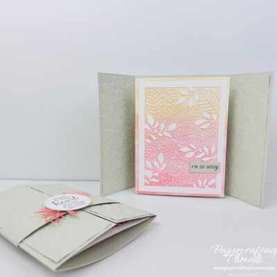 Pop Out Gatefold Card with both closed and open versions. Card base is Basic Beige with embossed leaves and circle medallion on a belly band holding the gatefold sides closed. When opened, a watercolor pink/yellow background springs forward and has a leafy pattern die cut overlay.