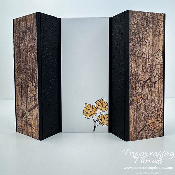 Triple Panel Standing Card Back View. Two narrow panels with a wood-grain paper accented with stamped leaves flank a wider white central panel with a leaf accent on a black card base. Two leaf-embossed narrow strips flank the center panel.